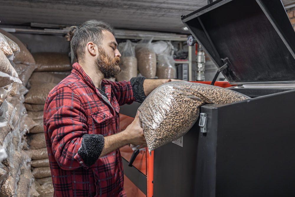 man-loads-pellets-solid-fuel-boiler-working-with-biofuels-economical-heating man loads pellets solid fuel boiler working with biofuels economical heating